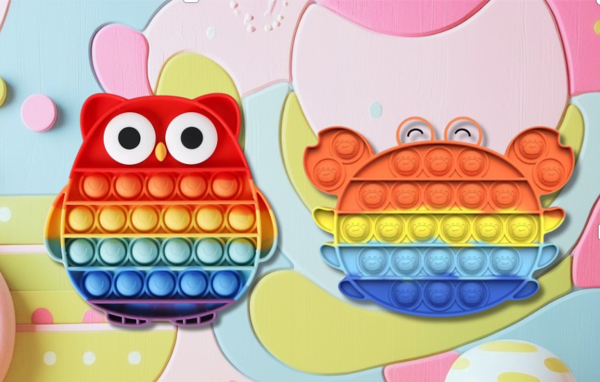 Two sensory popper toys in the shapes of an owl and a crab, with a rainbow color pattern.